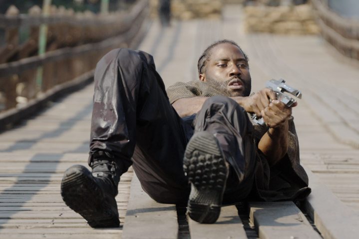 John David Washington points a gun while on the ground in The Creator.